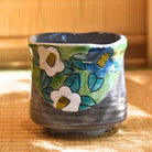 Ceramic cup with floral design on a woven mat