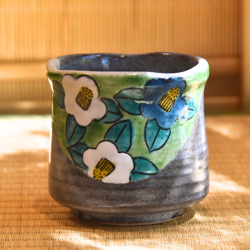 Ceramic cup with floral design on a woven mat
