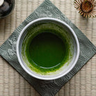 Green tea in a white cup on a textured mat
