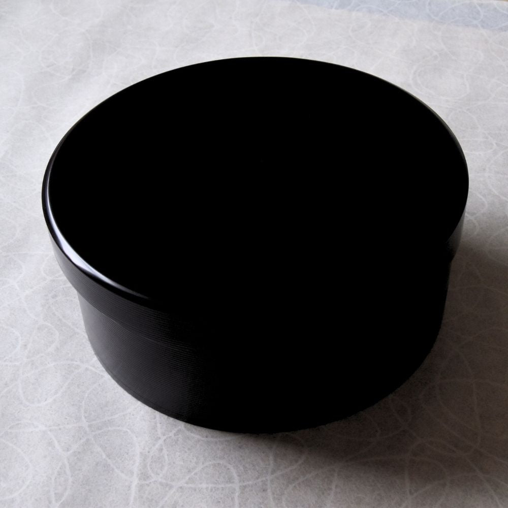 Black ceramic container on a textured white surface