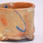 Ceramic cup with orange and blue abstract design on a white background