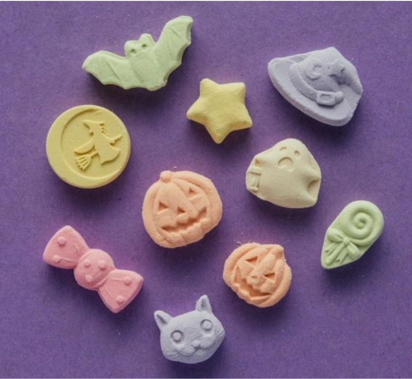 Colorful candy molds shaped like various objects on a purple background