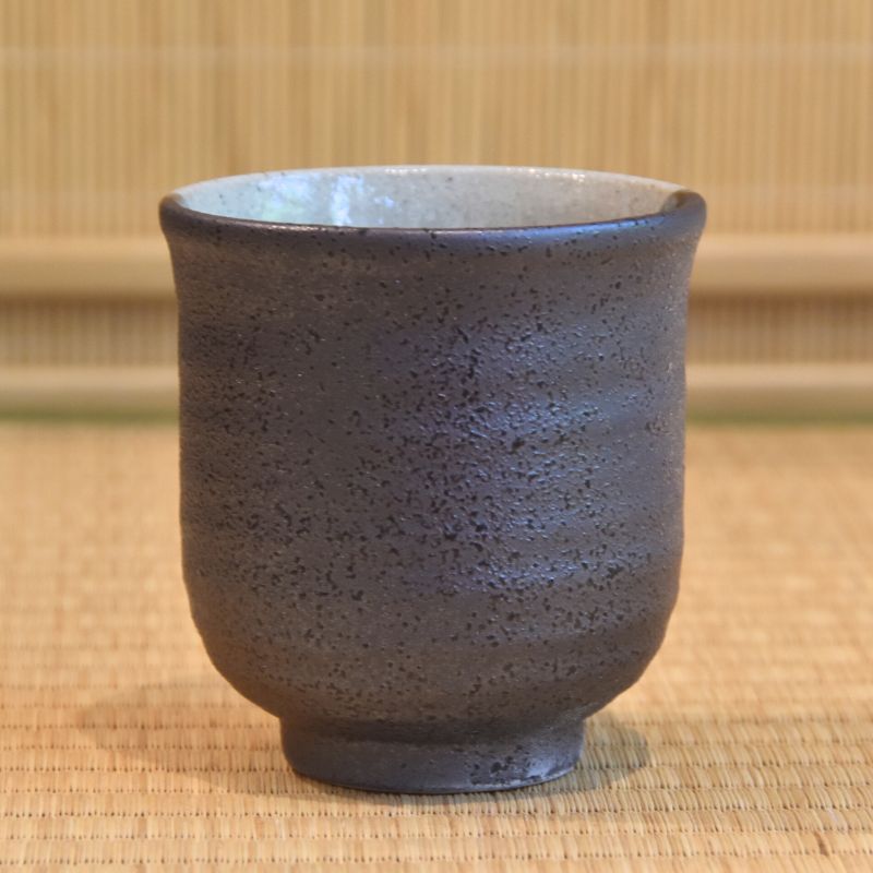 Dark brown ceramic cup on a textured surface