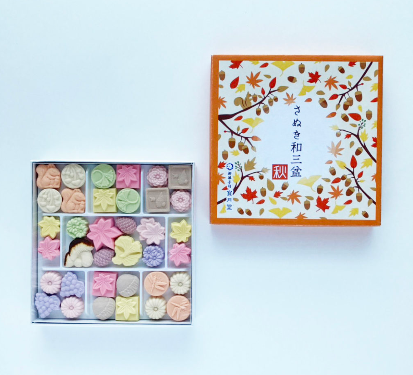 Box of assorted pastries with a decorative lid featuring an illustration on a white background