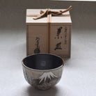 Ceramic cup with decorative patterns in front of a wooden gift box on a light background