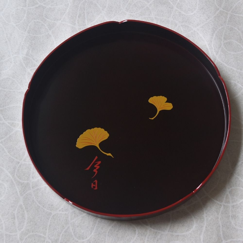 Black lacquerware with gold leaf design on a textured white background
