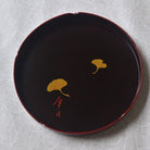 Black lacquerware with gold leaf design on a textured white background