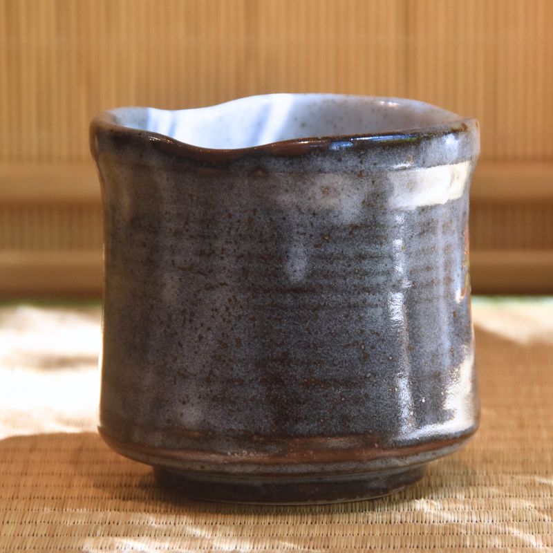 Ceramic cup with a textured surface on a woven mat