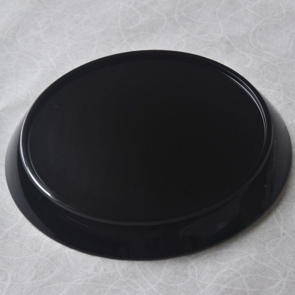 Black round tray on a textured gray surface