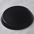 Black round tray on a textured gray surface