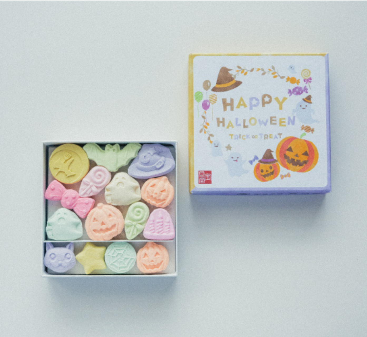 Box of colorful Halloween-themed bath bombs with a decorative box on a light background