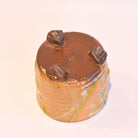 Cylindrical object with three protruding elements on a light pink background