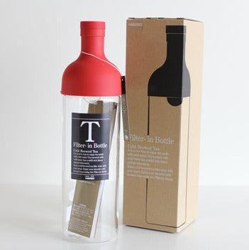 Red bottle with clear label and cardboard box on a white background