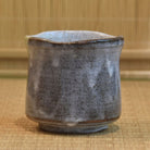 Hexagonal ceramic cup with a textured surface on a woven mat background