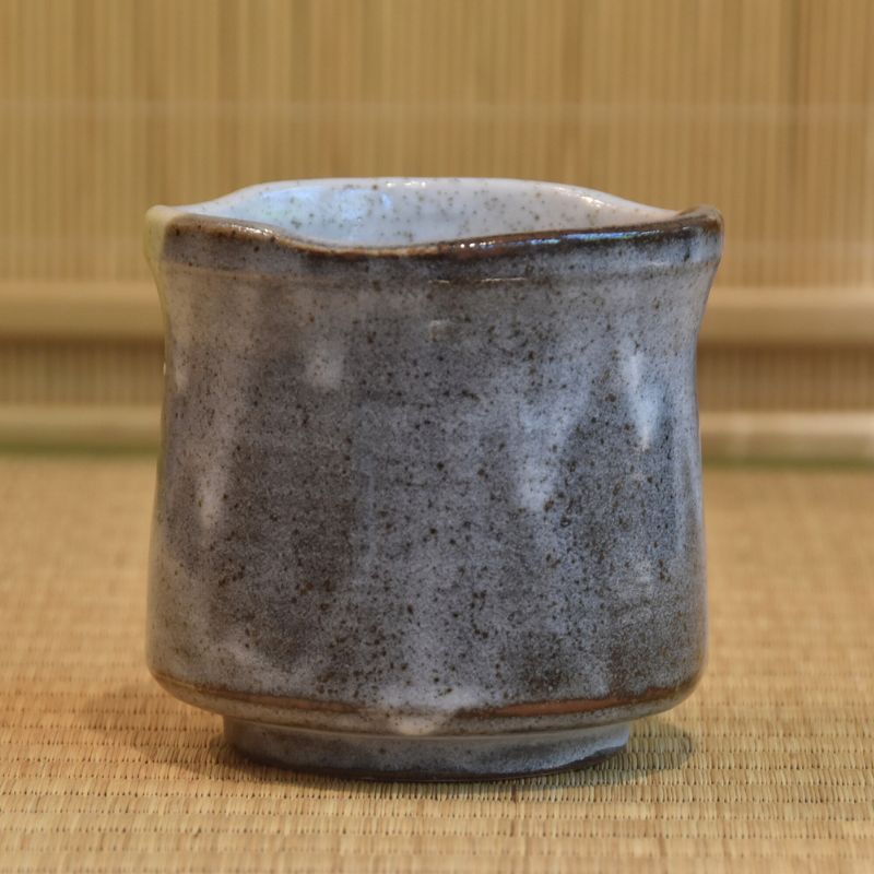 Hexagonal ceramic cup with a textured surface on a woven mat background