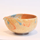 Ceramic bowl with abstract orange and blue designs on a white background