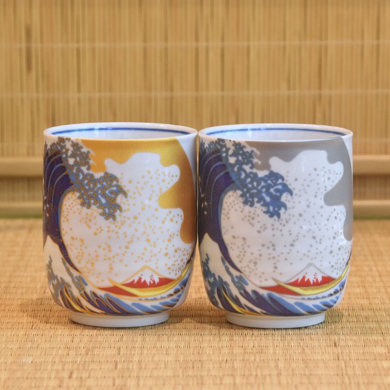 Two ceramic cups with wave and mountain design on a woven mat background