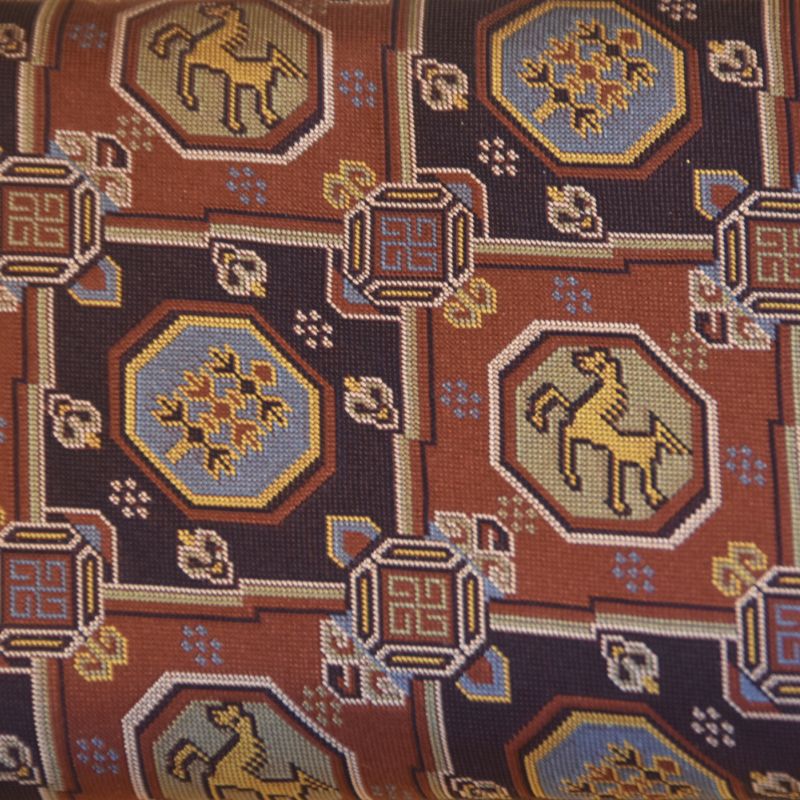 Close-up of a patterned fabric with geometric shapes and horse illustrations.