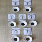 Tea leaves in small white bowls with packaging on a textured surface
