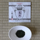 Tea packaging and a bowl of tea leaves on a woven mat