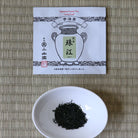 Tea packaging with a bowl of black tea leaves on a woven mat