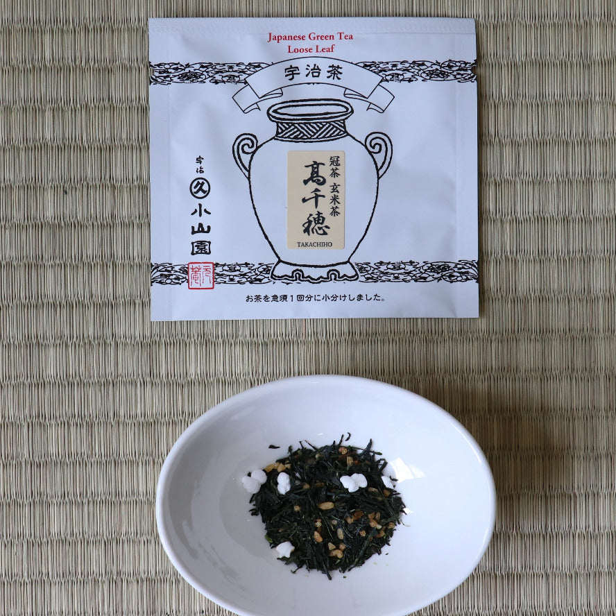 Tea leaves in a small white bowl next to a tea package on a woven mat