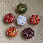 Set of six folded fabric ornaments on a textured surface