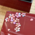 Red cosmetic case with floral design on a wooden surface