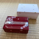Red decorative box with floral patterns on a woven surface