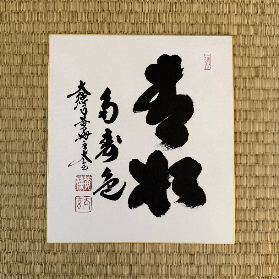 Calligraphy piece on a white sheet with black ink on a textured brown background