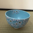 Blue ceramic bowl with floral design on a woven mat