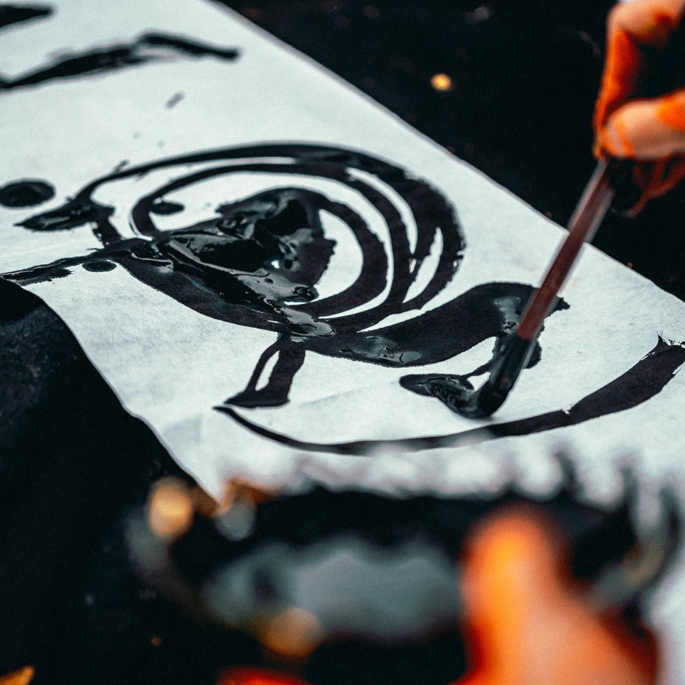 Person writing calligraphy with a brush on rice paper