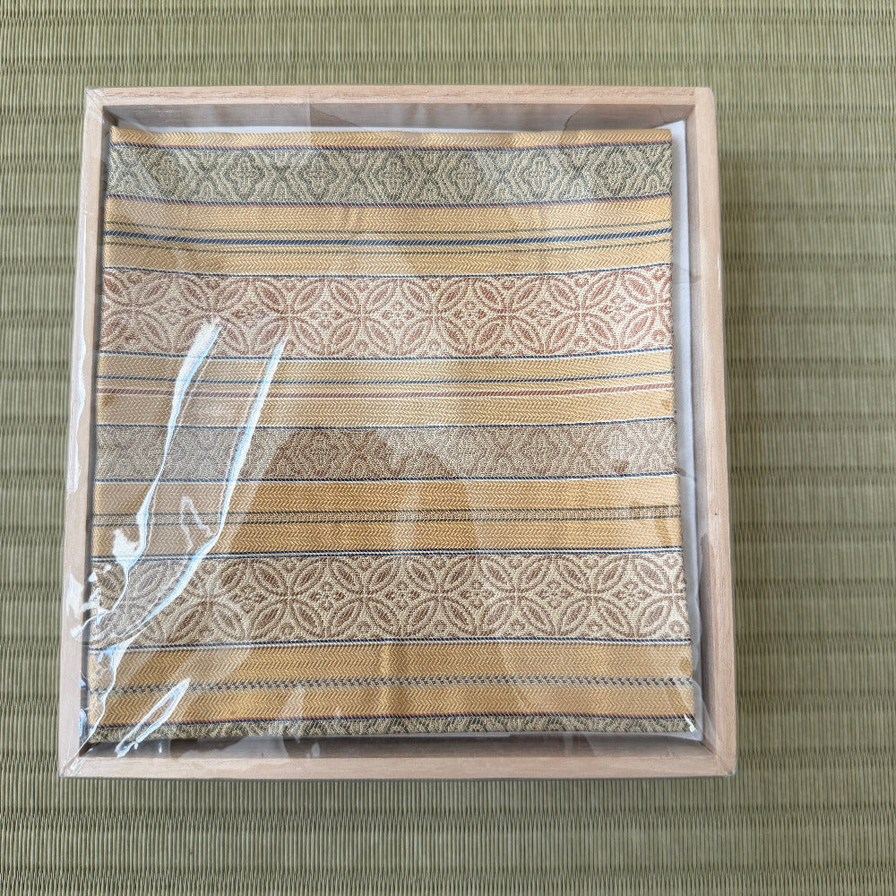 Patterned fabric in a wooden frame on a green textured background
