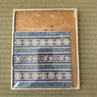 Decorative fabric with blue and white patterns in a box on a textured green background