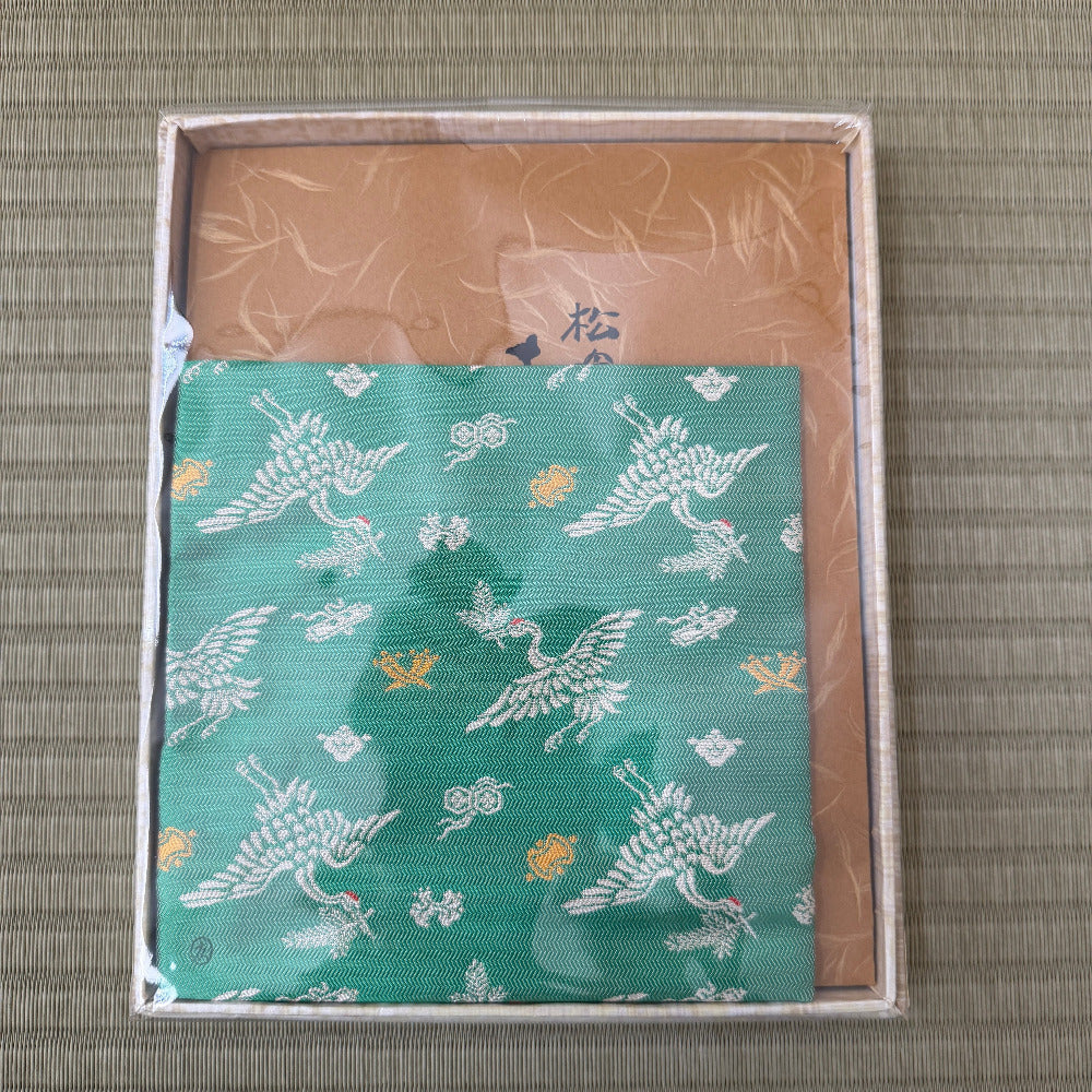Teal fabric with bird pattern in a box on a textured surface