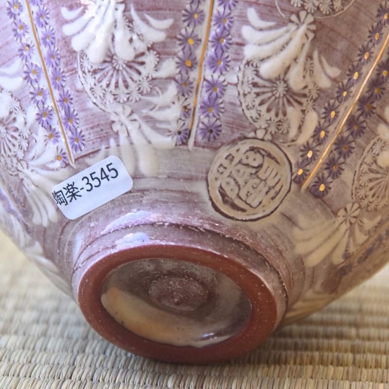 Close-up of a ceramic bowl with intricate designs and a visible brand label on a woven surface.
