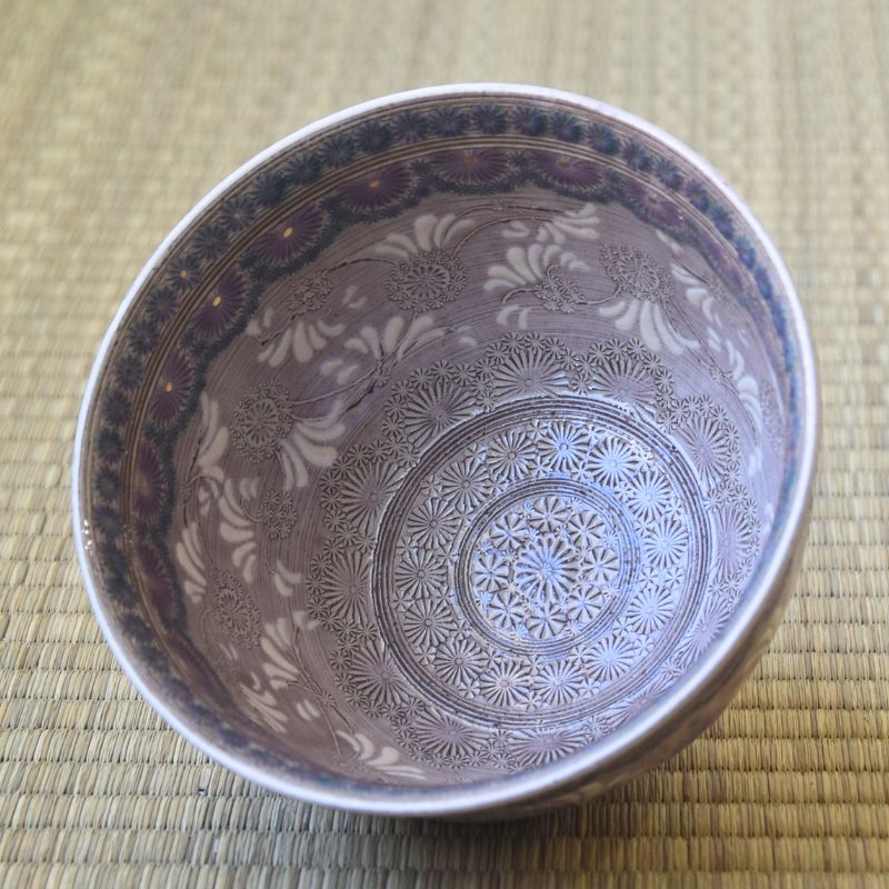 Decorative ceramic bowl with intricate patterns on a textured surface