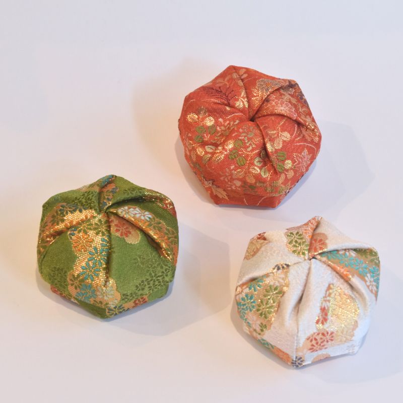 Three fabric origami balls in green, red, and multicolor on a white background