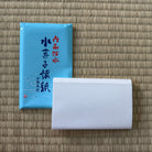 Blue packaging with text and a white product on a woven mat background