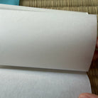 Roll of white paper held by a hand on a textured surface