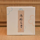 Beige notebook with floral designs and a label on a woven background