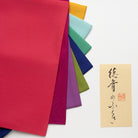 Colorful paper sheets in various colors with a small card featuring Japanese text on a white background.