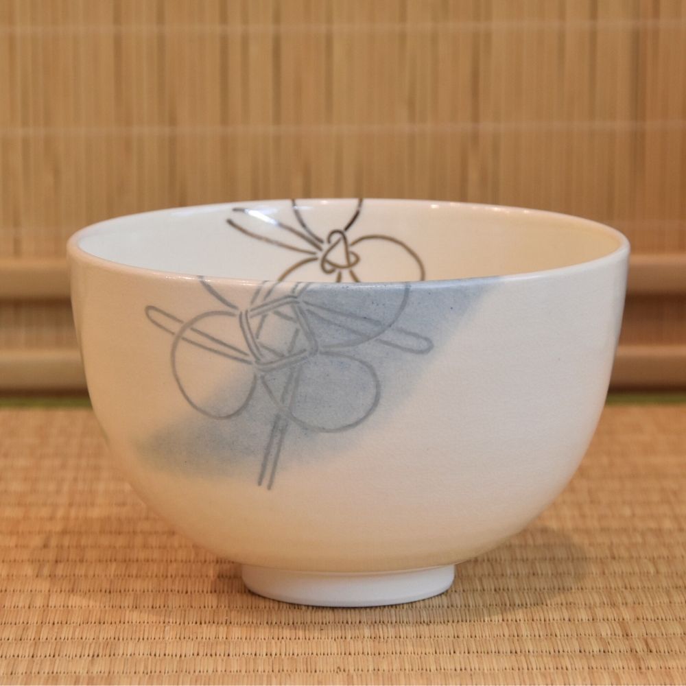 White ceramic bowl with gray floral design on a woven mat