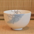 White ceramic bowl with gray floral design on a woven mat