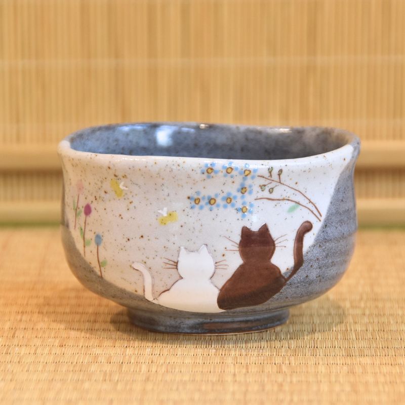 Ceramic cup with cat illustrations on a woven mat background