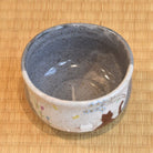 Ceramic bowl with speckled design on a woven mat