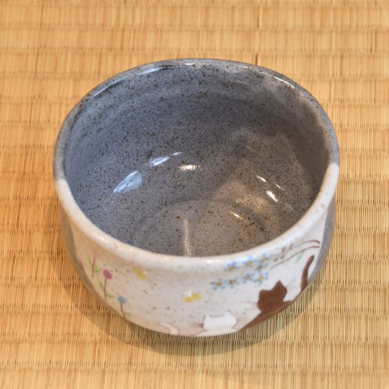 Ceramic bowl with speckled design on a woven mat