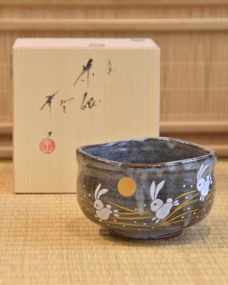 Ceramic bowl with bunny illustrations on a wooden surface, with its box in the background
