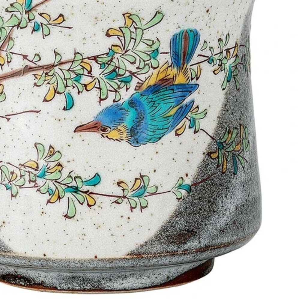 Ceramic mug with a blue bird and green leaves design on a white background