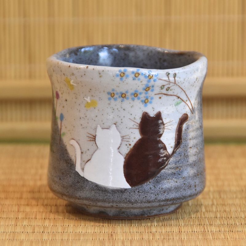 Ceramic cup with cat design on a woven mat background